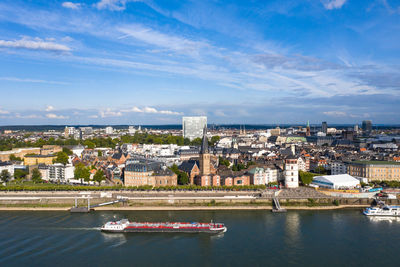 Buildings by river against sky in city