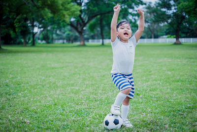 Full length of boy playing soccer on grass