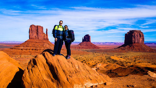 Man standing on rock formation against sky