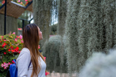 Rear view of woman standing by flowering plants