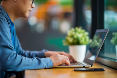 Midsection of man using mobile phone while sitting on table