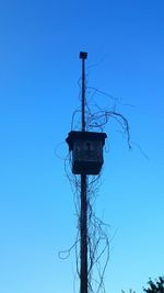 Low angle view of telephone pole against clear blue sky