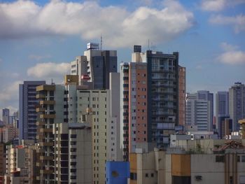 Buildings in city against cloudy sky