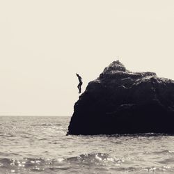 Rock formation in sea against clear sky