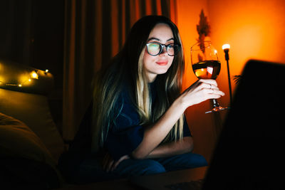 Portrait of young woman sitting in illuminated room