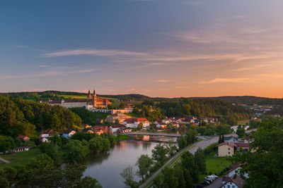 High angle view of river amidst buildings against sky at sunset