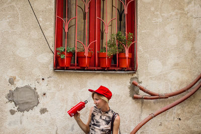 Full length of child standing against red wall