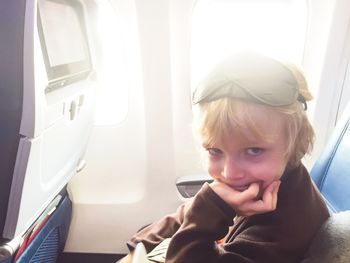Portrait of boy sitting in airplane on sunny day