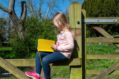 Full length of woman sitting on bench in park