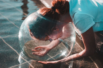 Close-up of woman wearing glass container at lake