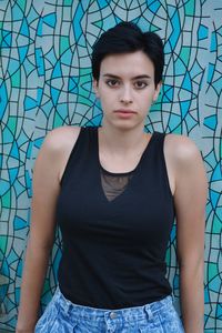 Portrait of young woman standing against wall