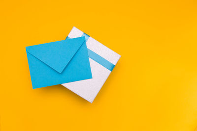 High angle view of box with envelop over yellow background