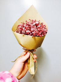 Close-up of hand holding ice cream over white background