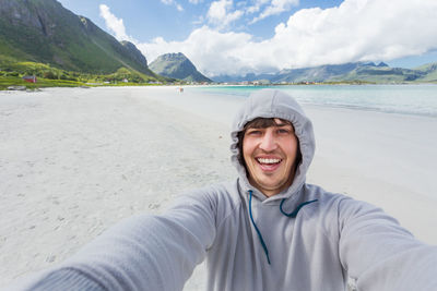 Tourist man making selfie on rambergstranda beach on lofoten islands. beautiful sandy beach.norway.