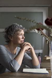 Thoughtful mature woman sitting by table at home