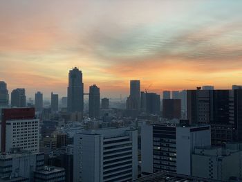 Modern buildings in city against sky during sunset