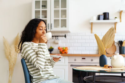African-american female drinking cup of tea and enjoying morning. concept of slow-living lifestyle