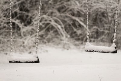 Snow covered swings hanging at playground