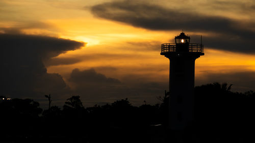 Lighthouse by sea against sky during sunset