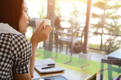 Midsection of man holding coffee cup on table