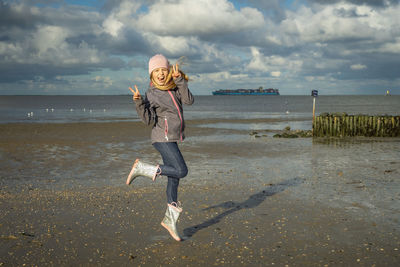 Full length of girl on beach against sky