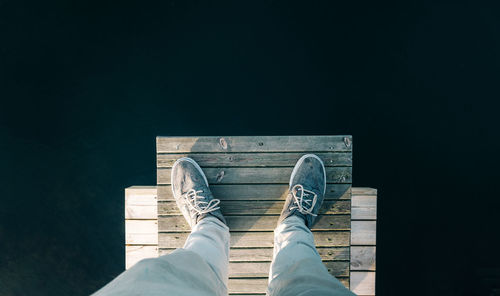 Low section of man standing on pier over sea