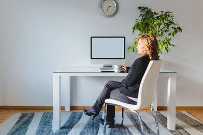 Full length of woman sitting on table at home