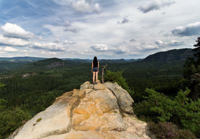 Rear view of woman standing on rock formation against sky at hantzschelstiege