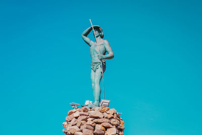 Full length of shirtless man standing against blue background