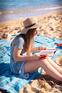 Rear view of woman sitting on lounge chair at beach