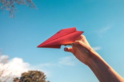 Close-up of hand holding umbrella against sky