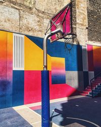 Low angle view of basketball hoop by colorful wall at sports court