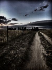 Road amidst agricultural field against sky during sunset