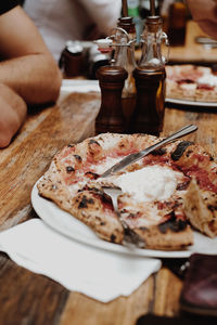 Close-up of hand by pizza on table