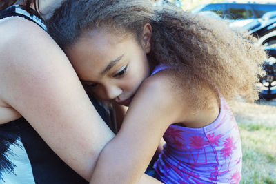 Girl embracing mother while sitting in yard