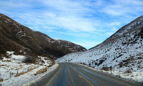 Road amidst snowcapped mountains against sky