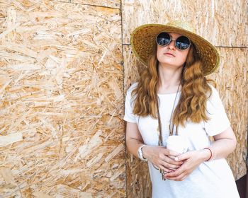 Beautiful young woman standing against wall