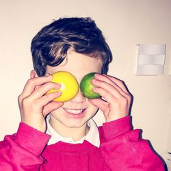 Close-up of boy holding citrus fruits while standing at home