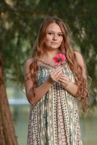 Portrait of young woman standing against blurred background