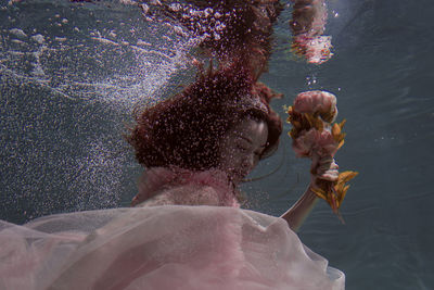 Woman holding flowers while swimming in pool