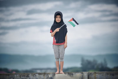 Portrait of young woman standing against sky