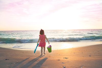 Rear view of boy on beach against sky