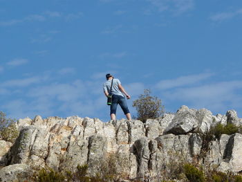 Man standing on rock against sky