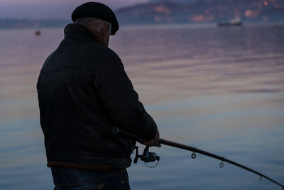 Man fishing at sea during sunset