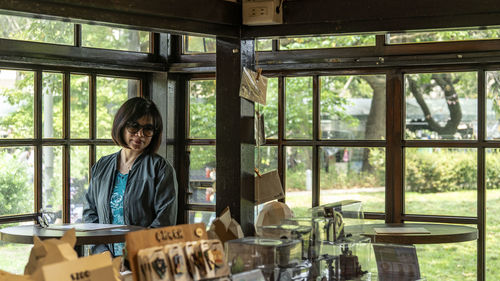 Portrait of a smiling young woman standing by window