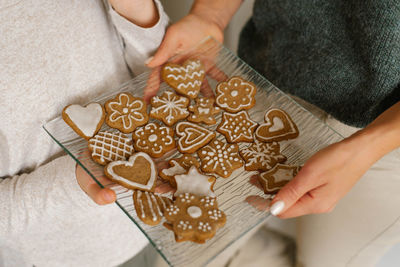 Christmas ginger cookies decorated with icing sugar on a glass plate in the hands of mom 