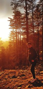 Man standing by trees in forest against sky