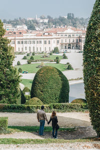 Rear view of couple holding hands while standing in park