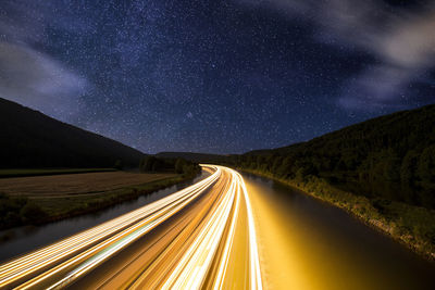 Light trails on road against sky at night