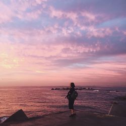 Man standing on beach against sky during sunset